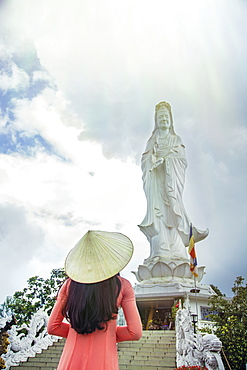 A young Vietnamese woman in a conical hat paying homage to Quan Am (Guanyin) at a Buddhist temple, Hue, Vietnam, Indochina, Southeast Asia, Asia