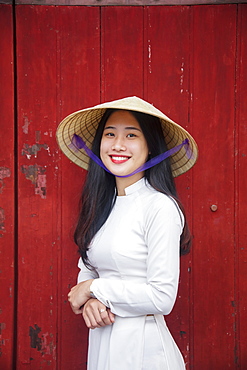 A young Vietnamese woman in traditional dress standing at the Western gateway to the Purple Forbidden City, Hue, Vietnam, Indochina, Southeast Asia, Asia