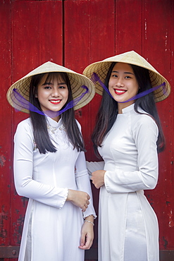 Two young women in traditional dress standing at the Western gateway to the Purple Forbidden City, Hue, Vietnam, Indochina, Southeast Asia, Asia