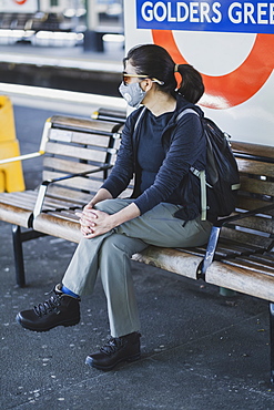 A woman wearing a protective hygiene (pollution) face mask on the London Underground subway system, London, England, United Kingdom, Europe