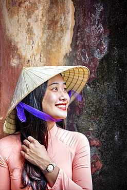 A young Vietnamese woman in a traditional Ao Dai dress and conical hat and smiling, Hue, Vietnam, Indochina, Southeast Asia, Asia