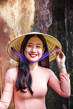 A young Vietnamese woman in a traditional Ao Dai dress and conical hat and smiling, Hue, Vietnam, Indochina, Southeast Asia, Asia