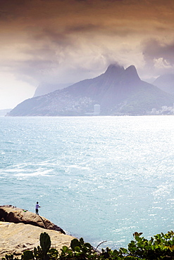 A fisherman on the Arpoador rocks next to Ipanema beach, Rio de Janeiro, Brazil, South America