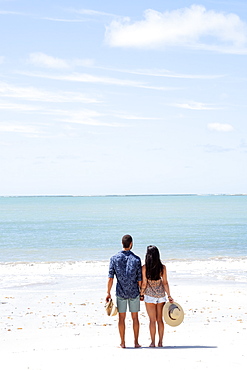 A good-looking Hispanic (Latin) couple on a deserted beach with backs to camera, Brazil, South America