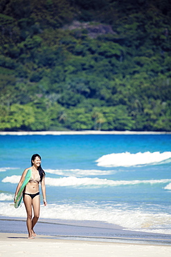 Beach shot of a Japanese Brazilian (Nipo-brasileiro) in a bikini carrying a surf board decorated with the Brazilian flag, Brazil, South America