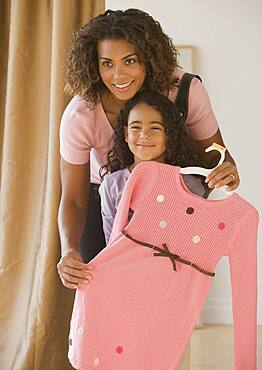 African mother holding dress up in front of daughter