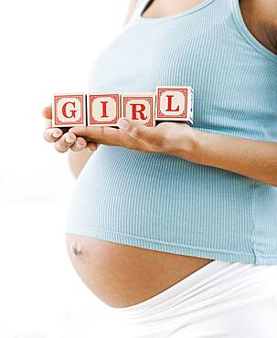 Pregnant African American woman holding 'GIRL' blocks