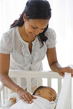 African American mother watching baby sleep