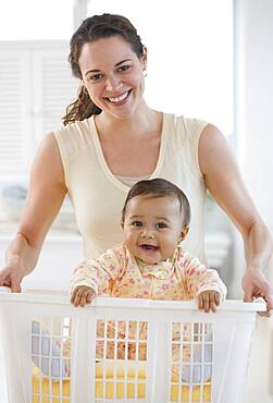 Hispanic mother carrying baby in laundry basket