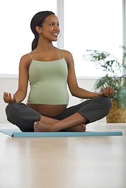 Pregnant African woman practicing yoga