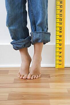 Boy standing on tiptoes next to ruler