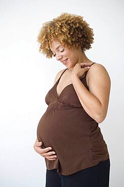 Pregnant African woman smiling at belly