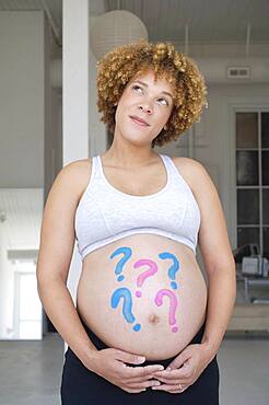 Pregnant African woman with question marks painted on belly