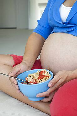 Pregnant African woman eating cereal