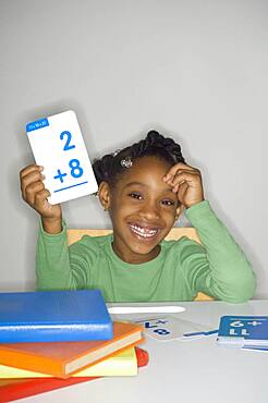 African girl holding addition flash cards