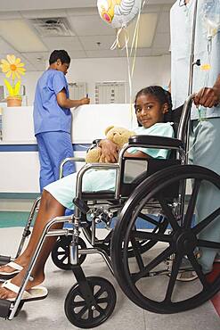 African girl being pushed in wheelchair in hospital