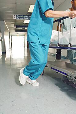 Nurse wheeling gurney in corridor of hospital