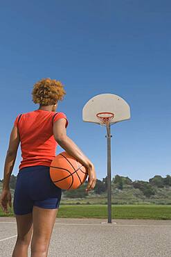 African woman holding basketball on court