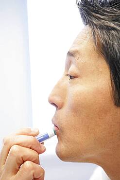 Asian man applying lip balm