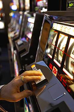 Man pushing the spin button on a slot machine