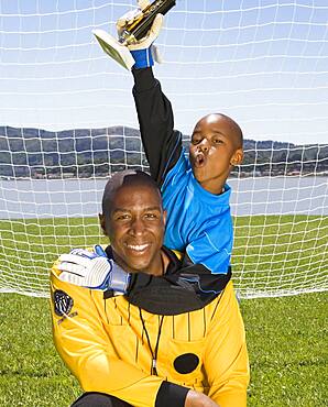 African boy and coach with soccer trophy