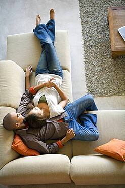 African American couple laying on sofa