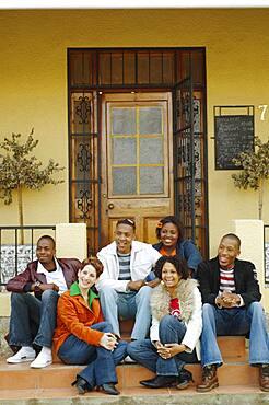 Multi-ethnic friends sitting on porch steps