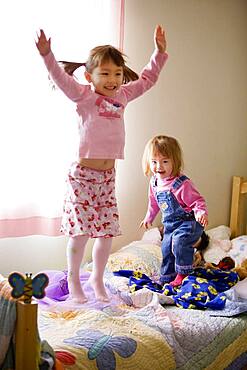 Two girls jumping on bed