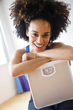 Mixed race woman holding scale