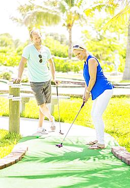 Caucasian couple playing miniature golf