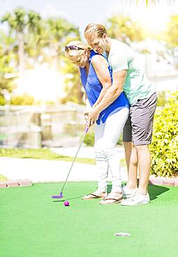 Caucasian couple playing miniature golf