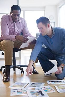 Businessmen examining paperwork on office floor