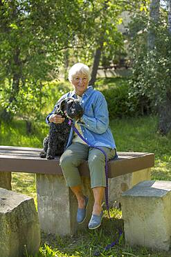 Older Caucasian woman hugging dog in park