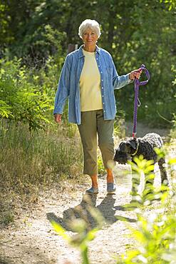 Older Caucasian woman walking dog on dirt path