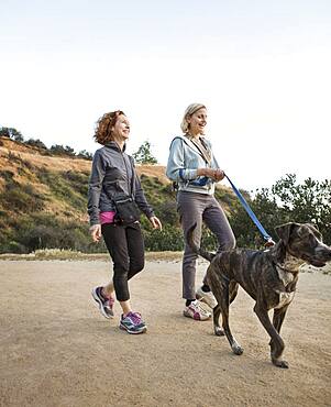 Caucasian women walking dog on dirt path