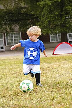 Caucasian boy playing soccer in field