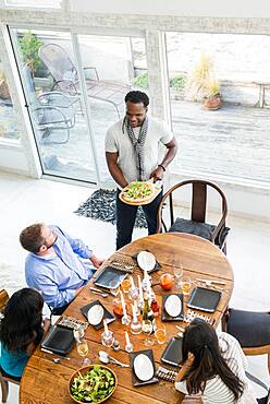 Man serving friends at dinner party