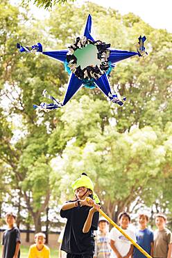 Blindfolded boy hitting pinata at party