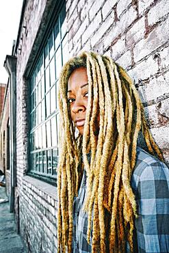 Black woman with dreadlocks at brick wall