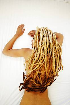 Black woman with dreadlocks laying on bed