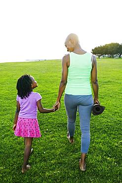 Mother and daughter holding hands in park