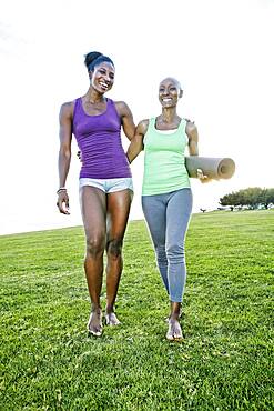 Women carrying yoga mat in park