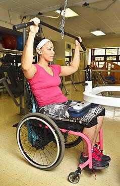 Paraplegic woman in wheelchair working out in physical therapy