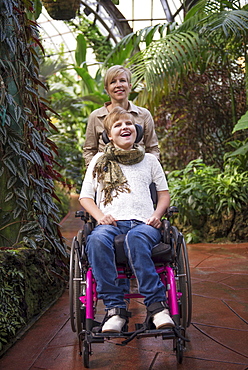 Mother pushing paraplegic daughter in wheelchair