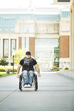 Disabled student rolling in wheelchair on college campus