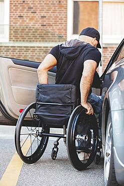 Disabled man in wheelchair climbing into car