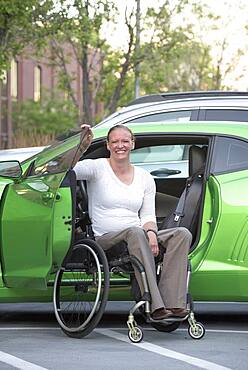 Disabled woman in wheelchair climbing into car