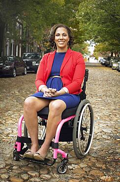 Disabled woman smiling in wheelchair on cobblestone street