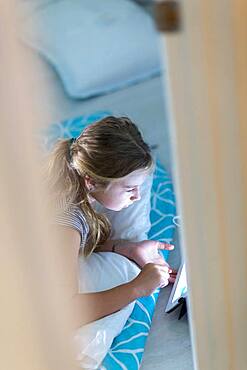 Caucasian girl using digital tablet on bed at night