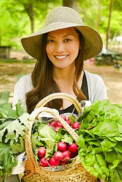 Asian woman carrying basket of produce